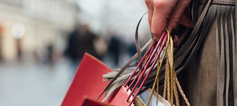 hand holding the straps of several retail holiday shopping bags